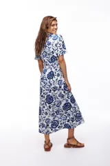 Vestido midi de algodón con estampado floral en tonos azul y blanco, corte camisero, cuello clásico, mangas cortas y cinturón con hebilla redonda de madera.
