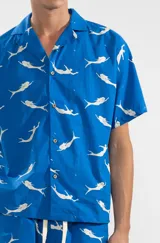 Camisa azul con estampado de sirenas blancas, de corte recto, manga corta y cuello camisero.
