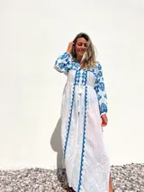 Túnica playera blanca traslúcida con bordados azules, mangas largas y abertura frontal.