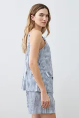 Chaleco con estampado a rayas verticales azules y blancas, con breteles finos y cierre frontal con botones. Presenta dos bolsillos frontales a la altura del pecho.