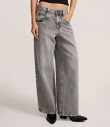 Pantalón skater de jeans con lavado dirty, tiro bajo, trabillas anchas, cierre con botón y cremallera, bolsillos delanteros y traseros, y bolsillo diferenciado.