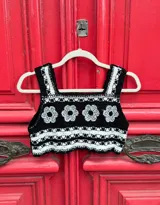 Top corto tejido al crochet, color negro con detalles en blanco y flores blancas.