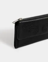 Billetera negra de cuerina con formato fichero y solapa bordada. Cuenta con sistema de apertura con broche a presión y compartimentos para tarjetas y billetes.