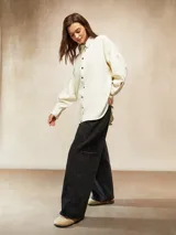 Camisa de pana fina color crudo, con cuello camisero, botones negros y mangas largas abullonadas con puños.