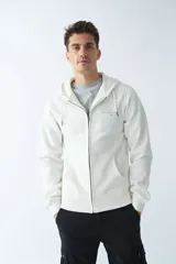 Campera de felpa color beige con cierre frontal, capucha con cordón ajustable, bolsillos laterales y logo estampado en el pecho.