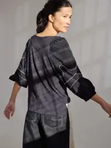 Remera gris de algodón con mangas color beige con bordados de líneas en blanco, amarillo y gris.