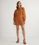 Mono corto color ladrillo, de sarga de algodón, con cuello mao, mangas abullonadas largas, cierre frontal con botones dorados, bolsillos laterales y cintura marcada.