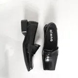 Mocasines negros de charol con punta cuadrada y detalle de antifaz.