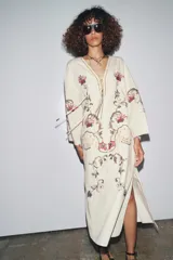 Vestido midi color crudo con bordados florales multicolores, escote en pico con lazos y mangas tres cuartos. Confeccionado en mezcla de algodón y lino.