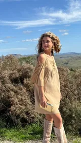 Vestido corto color beige, con escote en V con cordones, mangas 3/4 acampanadas con cordones y hombros descubiertos.