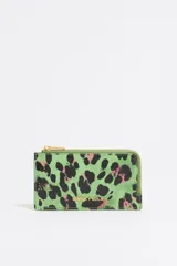 Monedero verde con estampado animal print en negro y rosa, cierre dorado con cremallera y logo de la marca en el frente.