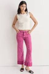 Pantalón de jean azul oscuro con corte acampanado, tiro medio y dobladillo en el ruedo. Presenta costuras marcadas en el frente y estampado abstracto en tonos grises y blancos en el interior del dobladillo.