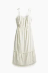 Vestido midi blanco con breteles finos ajustables, escote recto y cintura elastizada. Falda escalonada con volantes.