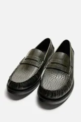 Mocasín de vestir color marrón oscuro con grabado tipo cocodrilo, horma redonda y suela con ligero tacón.