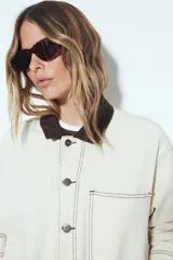 Sobrecamisa tipo barn jacket color negro, de algodón con elastano, con silueta relajada y estructura firme. Presenta cierre frontal con botones metálicos, cuello marrón, bolsillos aplicados y pespuntes visibles en color marrón.