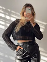 Remera de malla negra, de corte cropped con detalles traslúcidos.