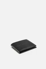 Billetera tipo cartera fabricada en piel color marrón oscuro. Cuenta con un compartimento para billetes, tres compartimentos para tarjetas, dos ranuras laterales y un monedero con cierre mediante clip.