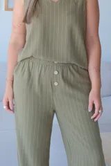 Pantalón ancho de tiro alto, color verde seco con finas rayas verticales blancas. Presenta cintura elastizada y dos botones decorativos frontales.