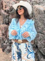 Camisa celeste de organza con volados en el frente y mangas largas abullonadas.