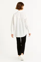 Camisa celeste de algodón, de corte holgado, con cuello clásico, cierre frontal con botones, bolsillo de parche en el pecho y mangas largas con puños abotonados.
