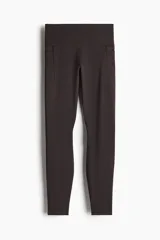 Calzas deportivas de tiro alto color marrón, confeccionadas en tejido funcional DryMove™ con bolsillos laterales.