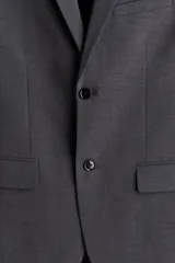 Blazer gris oscuro de botonadura sencilla, corte slim fit, con solapas de muesca finas, ojal decorativo, bolsillo superior, bolsillos delanteros con solapa, un bolsillo interior, cierre de dos botones, botones decorativos en los puños y abertura atrás.