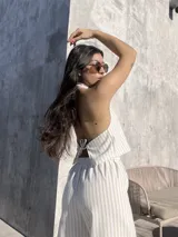 Top halter color beige con rayas verticales blancas y lazos ajustables en el frente y en la espalda.