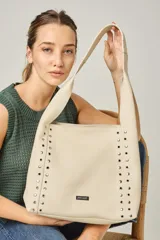 Cartera tipo shopper color negro, con apliques de tachas plateadas en los laterales y logo de la marca en la parte inferior.