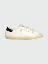 Zapatillas Golden Goose modelo Super Star, de cuero blanco con estrella calada y detalles en negro en el talón.