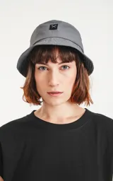 Gorro tipo bucket color gris oscuro con etiqueta con logo en el frente.