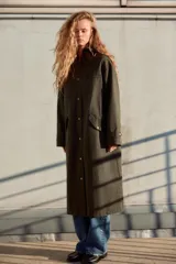 Trench color verde oscuro con cuello solapa combinado en pana marrón y manga larga. Detalle de acabados con trabillas y pinza en espalda. Bolsillos delanteros con solapa y botón a presión. Tejido encerado efecto lavado. Cierre frontal con botones a presión.