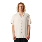 Camisa de manga corta color beige claro, con cuello cubano y botones frontales marrones. Presenta una textura sutilmente tejida.