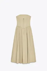Vestido midi color beige, de corte recto, con escote palabra de honor y hombros descubiertos. Confeccionado en tejido con efecto lavado y detalle de pliegues. Cierre trasero con cremallera metálica.