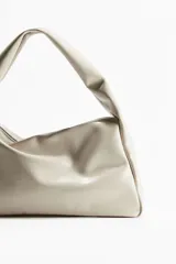 Cartera color crema de tejido revestido con cierre superior y asa ancha.