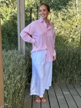 Camisa holgada a rayas verticales color beige y blanco, con cuello clásico, manga larga, bolsillo en el pecho y cierre frontal con botones nacarados.