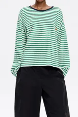 Camiseta de algodón con estampado de rayas horizontales verdes y blancas, cuello redondo con ribete azul marino, mangas largas y logo bordado en el pecho.