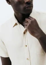 Camisa celeste de manga corta con cuello clásico, cierre frontal con botones y bolsillo de parche en el pecho. Corte recto.