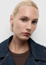 Campera corta de algodón estilo denim, color azul oscuro, con cuello solapado, cierre frontal, trabillas en los hombros y puños, y cinturón tipo batín. Presenta costuras contrastantes y un calce oversize.