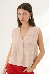 Chaleco de punto color rosa té con cuello en V y cierre frontal con botones.
