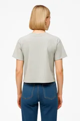 Remera color verde claro de algodón con cuello redondo y mangas cortas. Estampado frontal con dibujo de una pierna estilizada con zapato de tacón y corazones.