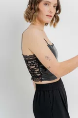 Top crop negro de cuero ecológico con tirantes finos y espalda de encaje floral con base nude.