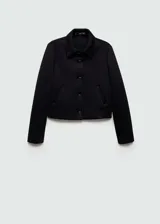 Chaqueta corta negra con cuello camisero, cierre frontal con botones, dos bolsillos laterales y forro interior.