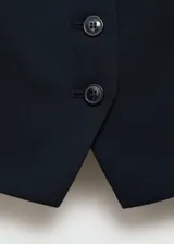 Chaleco azul marino con cuello en V, cierre frontal con botones y dos bolsillos de ribete delanteros. Diseño recto y sin mangas.