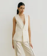 Chaleco sastrero color crema de lino, con cuello en V profundo y cierre cruzado con botón.