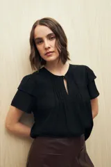 Blusa blanca de tela liviana con mangas cortas con volados y botón de nácar.