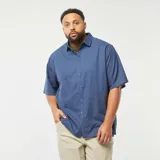 Camisa azul de manga corta con cuello clásico y cierre frontal con botones. Corte holgado.