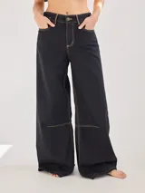 Pantalón ancho negro de algodón y lino con costuras en color mostaza, pinzas debajo de la rodilla y bordado de monograma en el bolsillo delantero.