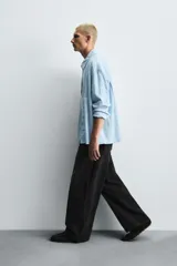 Pantalón de jeans de algodón, corte baggy fit, tiro medio, con efecto lavado en tonos grises y verdes. Presenta cinco bolsillos y cierre frontal con cremallera y botón.