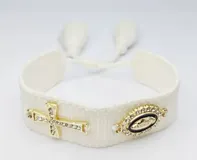 Pulsera tejida color gris con cierre ajustable y dijes dorados: una cruz con strass y un dije ovalado con la imagen de la Virgen María rodeada de strass.