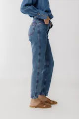 Pantalón de jean azul oscuro, corte mom, con pespuntes rojos y confeccionado en 100% algodón.